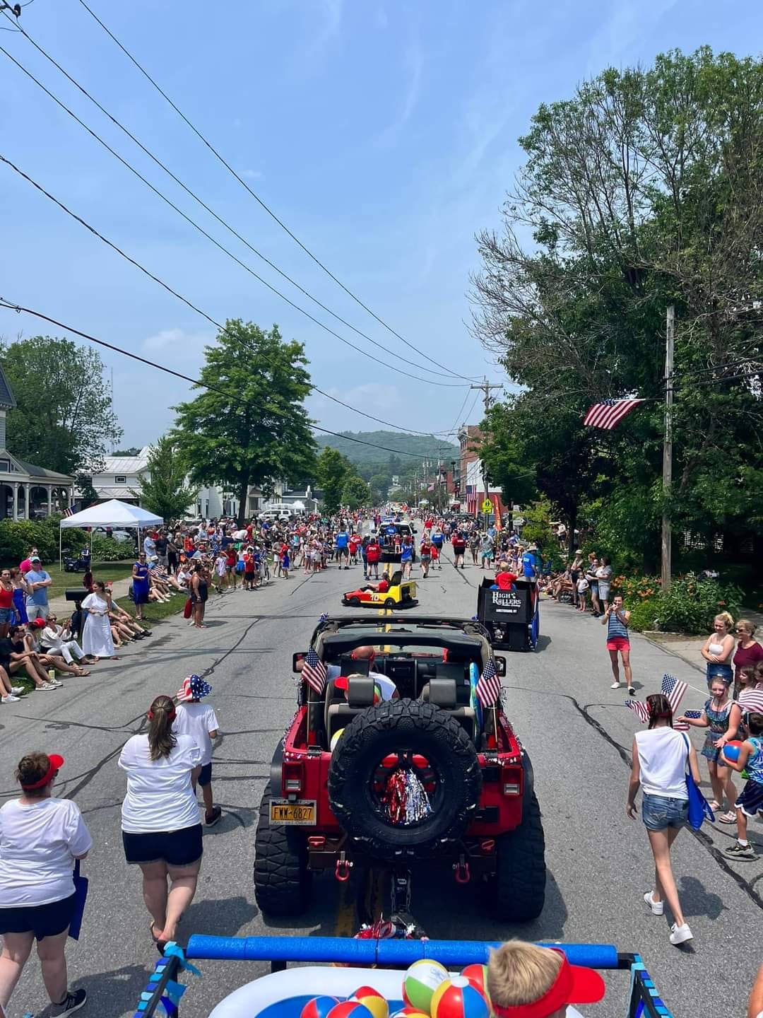 The Village of Northville's 4th of July parade marching down Main Street — fire trucks, marching contingents, and crowds lining the curbs